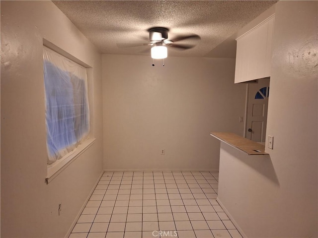 unfurnished dining area featuring light tile patterned floors, a textured ceiling, and ceiling fan