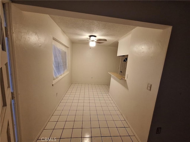 unfurnished room featuring ceiling fan, light tile patterned flooring, and a textured ceiling