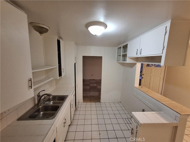 kitchen featuring tile countertops, light tile patterned flooring, white cabinetry, and sink