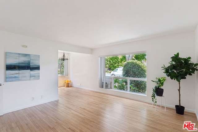 unfurnished living room with light hardwood / wood-style floors and an inviting chandelier