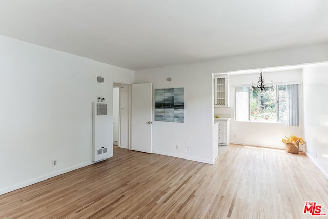 unfurnished room with an inviting chandelier and light wood-type flooring