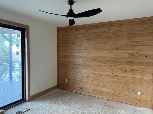 spare room with ceiling fan and wood walls