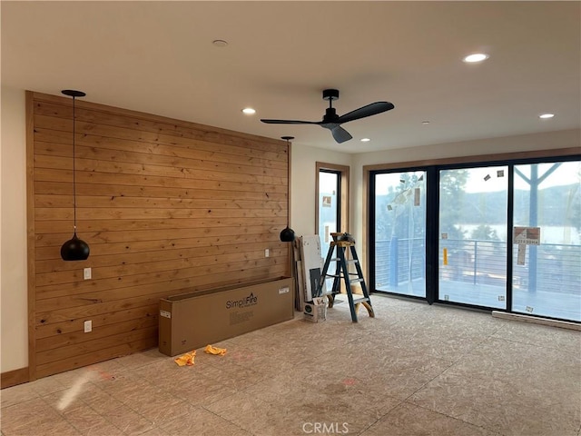 unfurnished room with ceiling fan and wood walls