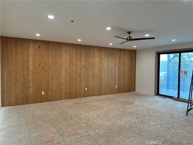 spare room featuring ceiling fan and wood walls