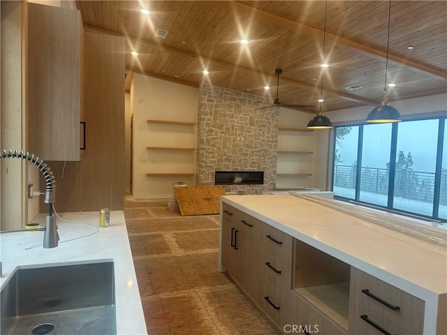 kitchen featuring wood ceiling, built in features, hanging light fixtures, a stone fireplace, and light brown cabinets