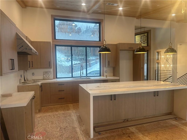 kitchen featuring a towering ceiling, pendant lighting, light brown cabinetry, sink, and a center island