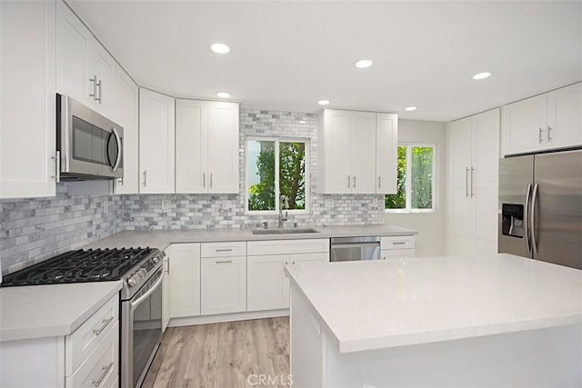 kitchen featuring appliances with stainless steel finishes, light hardwood / wood-style flooring, sink, and a healthy amount of sunlight