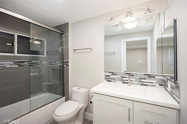 full bathroom with decorative backsplash, combined bath / shower with glass door, toilet, and vanity