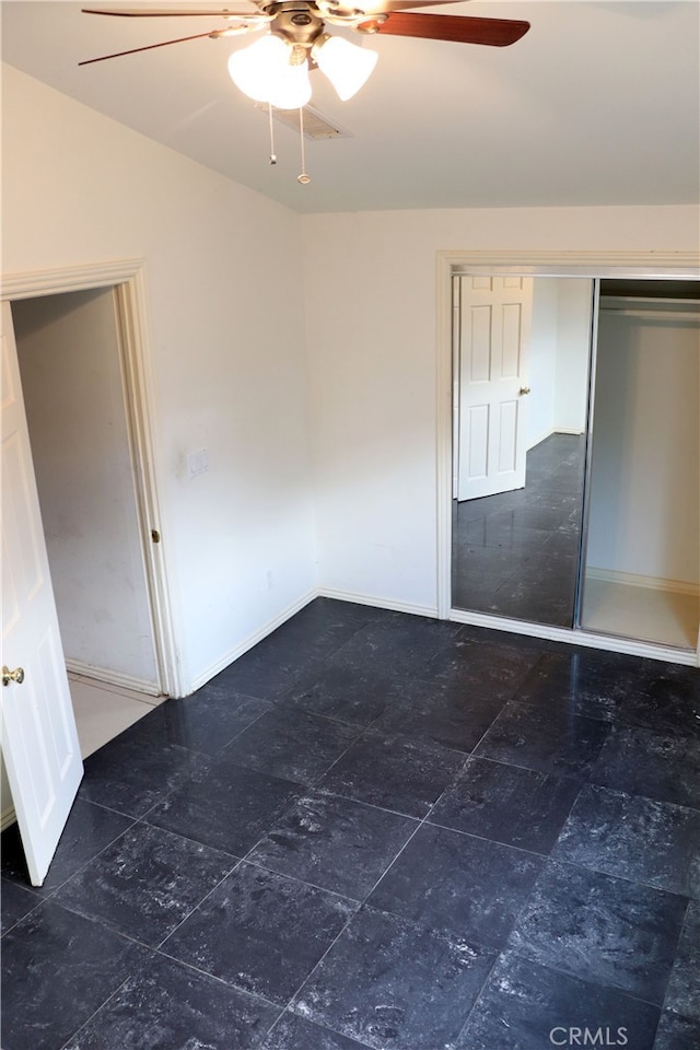 unfurnished bedroom with a closet, ceiling fan, and dark tile floors