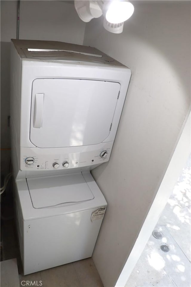 washroom with stacked washer and dryer and tile floors