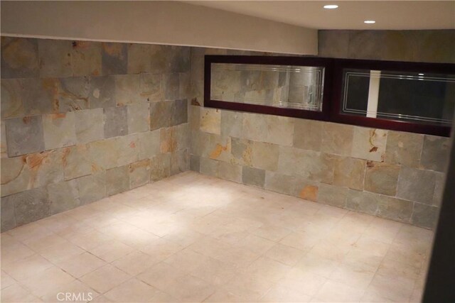 tiled spare room featuring tile walls