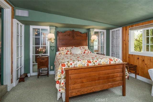 carpeted bedroom featuring wooden walls and vaulted ceiling