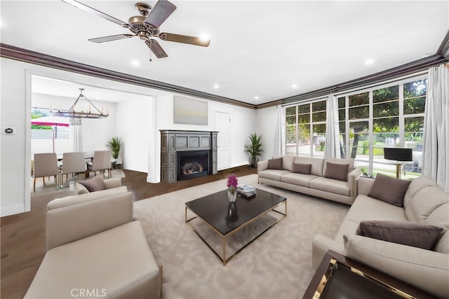 living room with a healthy amount of sunlight, wood-type flooring, ceiling fan with notable chandelier, and ornamental molding