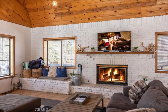 living room featuring vaulted ceiling, brick wall, a brick fireplace, and wood finished floors