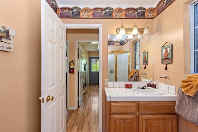 bathroom featuring hardwood / wood-style flooring, vanity, and a shower with shower door