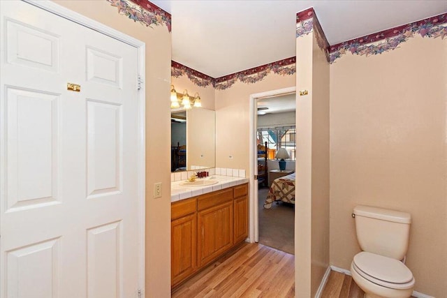 bathroom with hardwood / wood-style floors, vanity, and toilet