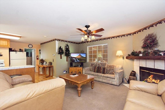 living room with ceiling fan, a tiled fireplace, and light carpet