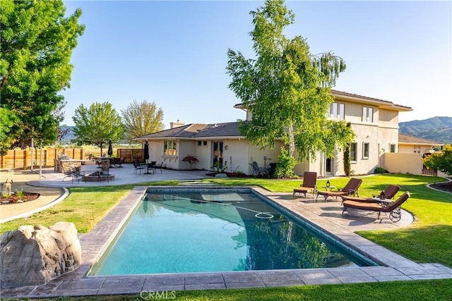 rear view of property with a lawn, a patio area, and a fenced in pool