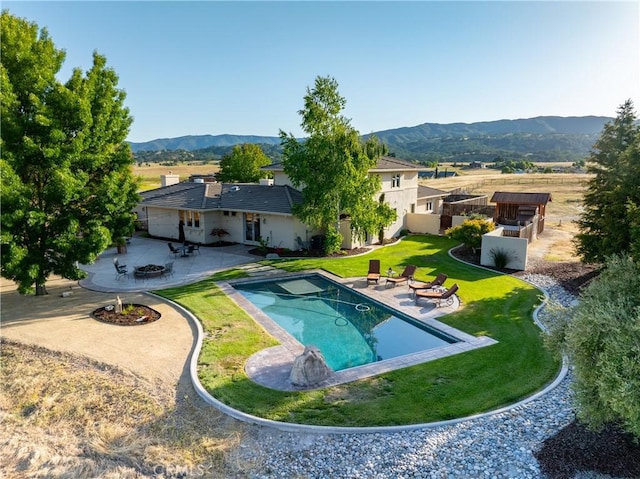 view of swimming pool with a mountain view, a patio, and a lawn