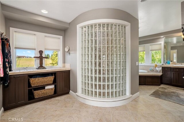 bathroom with tile patterned flooring, plenty of natural light, a washtub, and vanity