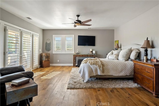 bedroom featuring ceiling fan, light wood-type flooring, and multiple windows