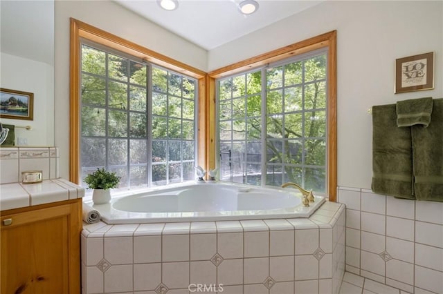 bathroom featuring vanity, a wealth of natural light, and a relaxing tiled tub