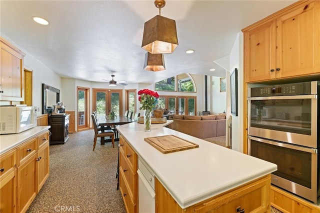 kitchen with ceiling fan, french doors, pendant lighting, double oven, and a center island