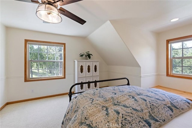 bedroom with ceiling fan, vaulted ceiling, multiple windows, and carpet flooring