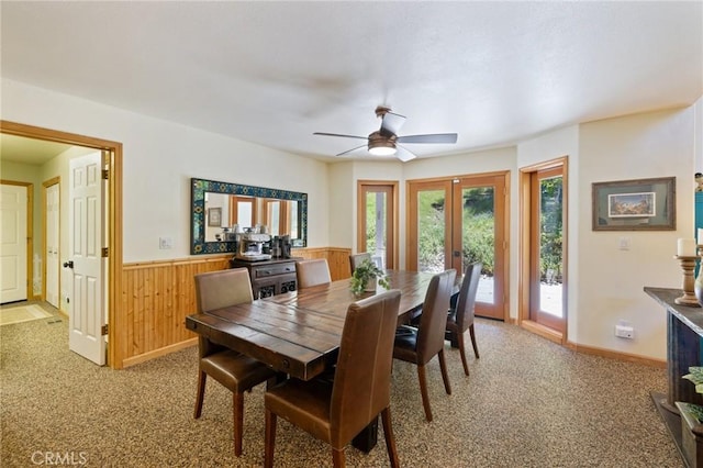 dining area with ceiling fan, french doors, wood walls, and carpet flooring