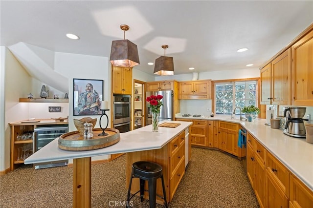 kitchen with a breakfast bar area, stainless steel appliances, light brown cabinets, pendant lighting, and sink