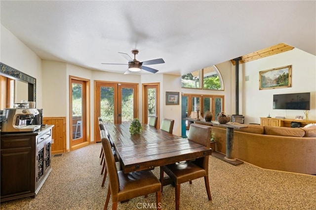 carpeted dining room featuring ceiling fan, french doors, and wooden walls