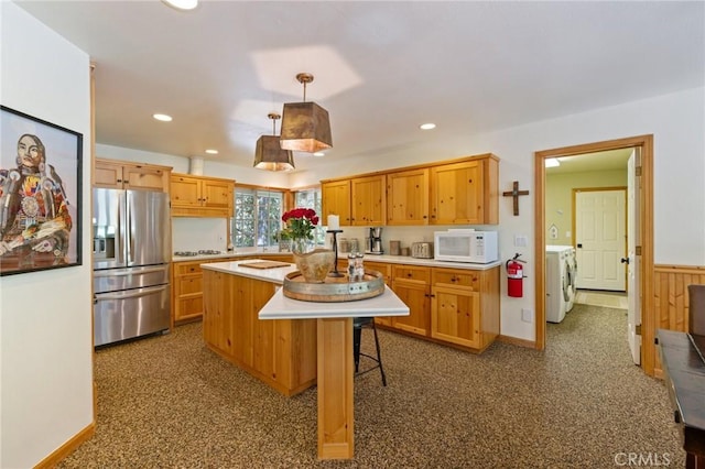 kitchen featuring stainless steel fridge, washing machine and clothes dryer, dark colored carpet, pendant lighting, and a center island