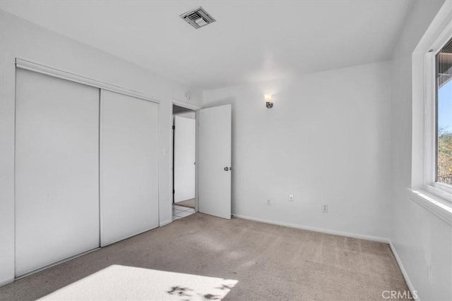 unfurnished bedroom featuring a closet and light carpet