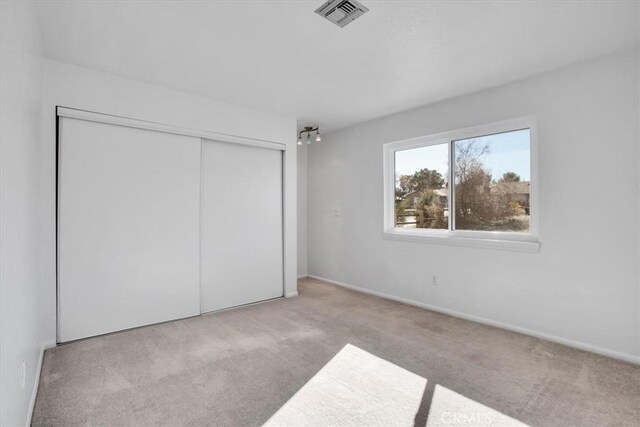 unfurnished bedroom with a closet and light carpet