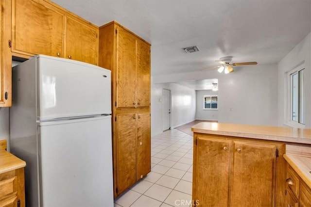 kitchen with white fridge, kitchen peninsula, light tile patterned flooring, and ceiling fan