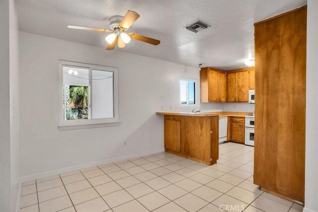 kitchen with white appliances, kitchen peninsula, light tile patterned floors, ceiling fan, and a textured ceiling