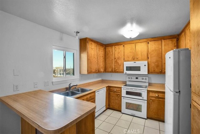 kitchen with white appliances, a textured ceiling, light tile patterned flooring, and kitchen peninsula