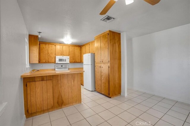 kitchen with white appliances, light tile patterned flooring, and kitchen peninsula