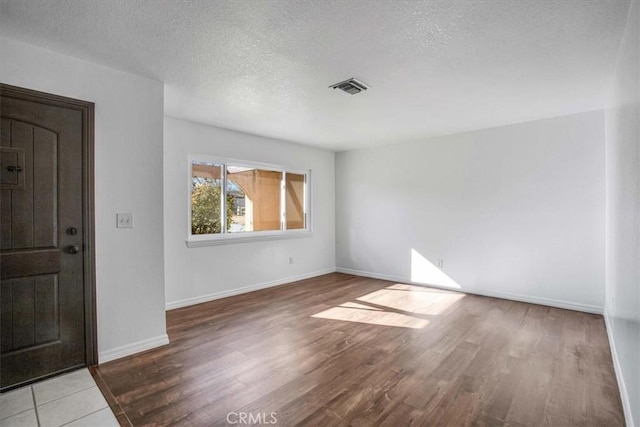 entrance foyer with a textured ceiling and light hardwood / wood-style floors