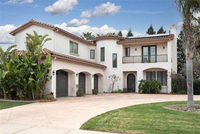 mediterranean / spanish home with a garage, a front yard, and a balcony