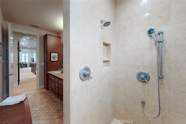 bathroom with tiled shower and vanity