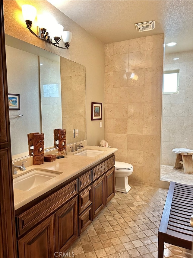 bathroom featuring dual sinks, tile walls, a textured ceiling, tile floors, and large vanity