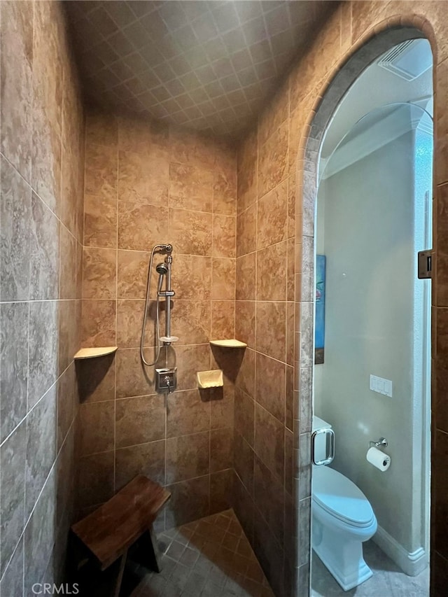 bathroom with a tile shower, tile flooring, and toilet