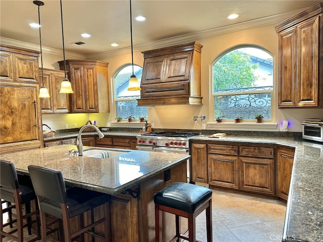 kitchen with an island with sink, sink, a kitchen breakfast bar, and crown molding