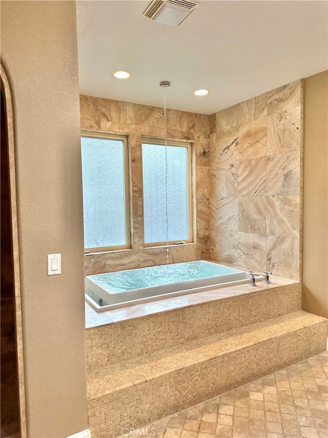 bathroom with tile walls, tile floors, and tiled bath