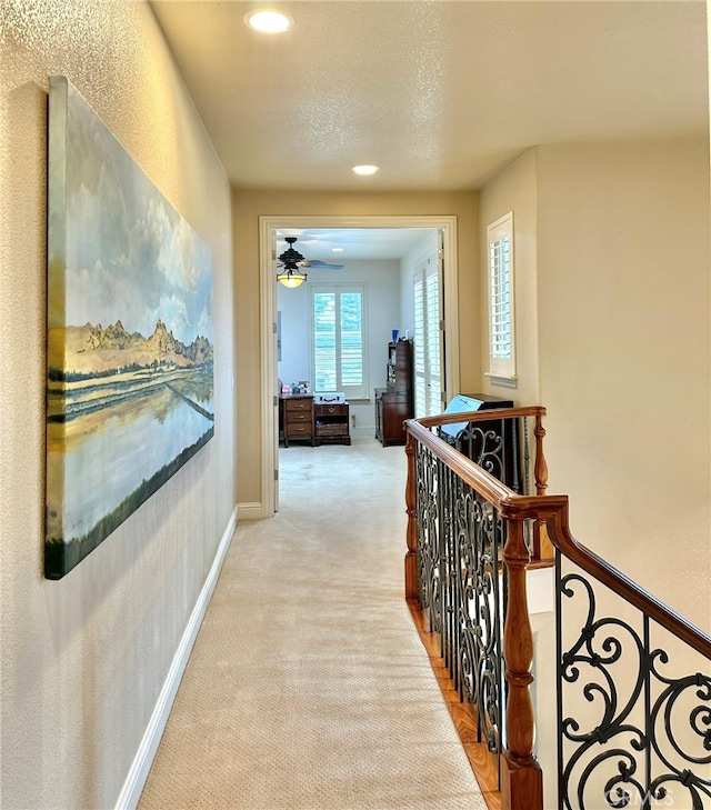 hallway featuring light carpet and a textured ceiling