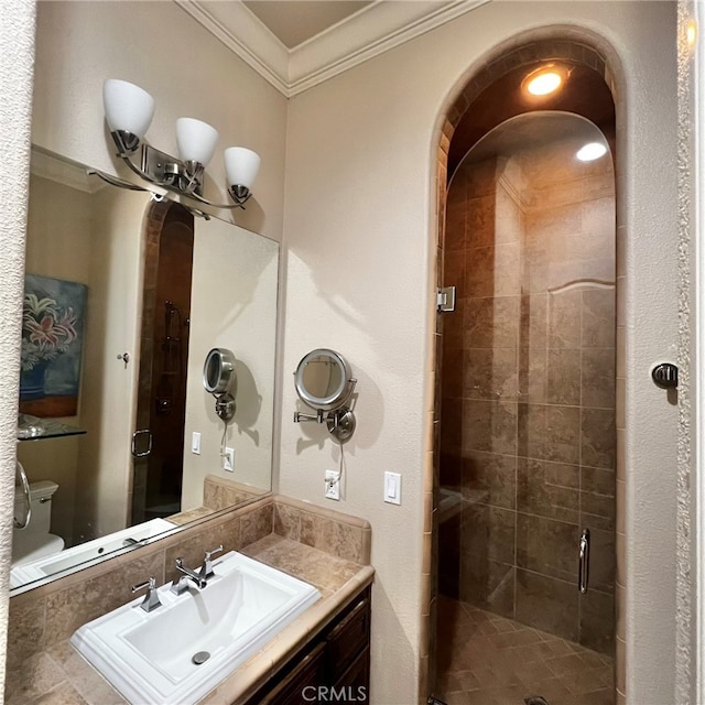 bathroom with vanity with extensive cabinet space, an enclosed shower, ornamental molding, and toilet