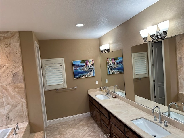 bathroom with an inviting chandelier, a bathing tub, dual vanity, tile flooring, and a textured ceiling