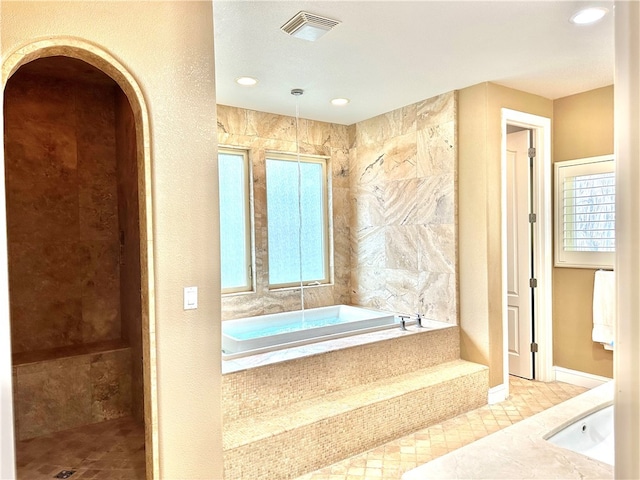 bathroom featuring tile flooring and tiled tub