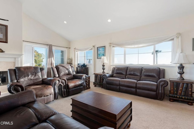 living room with light carpet, a tiled fireplace, and high vaulted ceiling